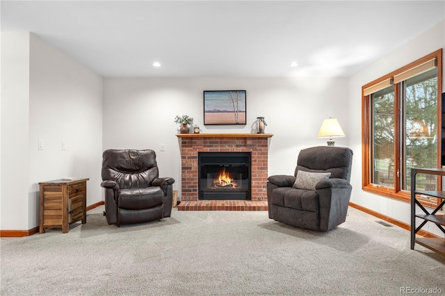 sitting room with baseboards, carpet flooring, a brick fireplace, and visible vents