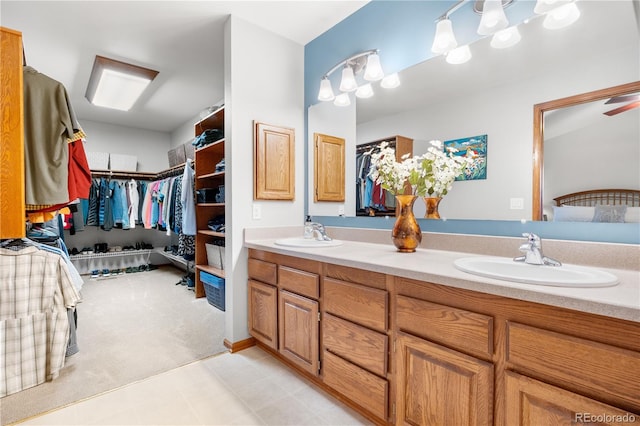 bathroom with double vanity, a sink, and a walk in closet
