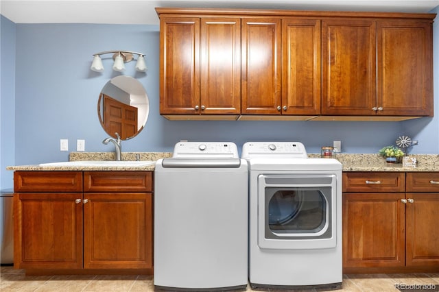 clothes washing area with a sink, washer and clothes dryer, and cabinet space