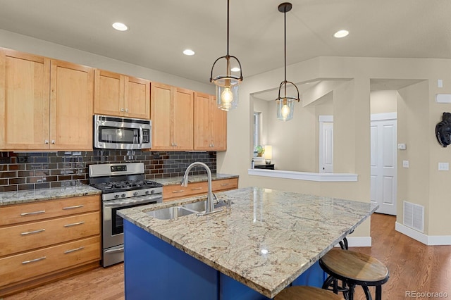 kitchen with appliances with stainless steel finishes, visible vents, a sink, and light wood finished floors