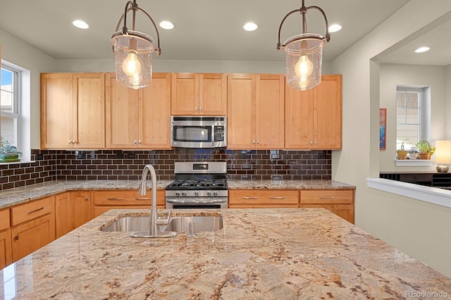 kitchen with appliances with stainless steel finishes, light brown cabinets, a sink, and decorative backsplash