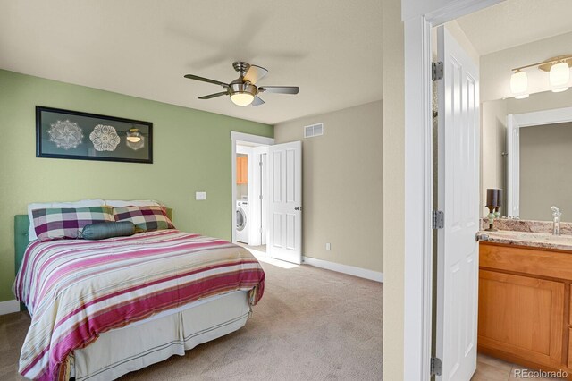 bedroom with light colored carpet, visible vents, a ceiling fan, baseboards, and washer / dryer