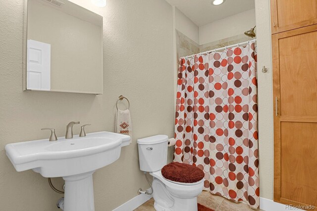 full bathroom with toilet, curtained shower, baseboards, and a sink