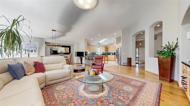 9559 Brook Hill Ln, Lone Tree, CO 80124 - living area featuring light wood-style floors, arched walkways, and vaulted ceiling