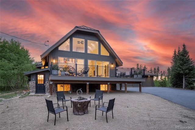 189 Pine Cone Ln, Winter Park, CO 80482 - back of house at dusk featuring an outdoor fire pit, a wooden deck, and stone siding