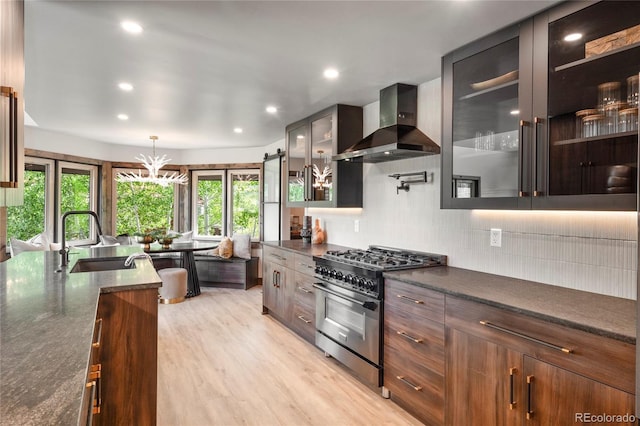 189 Pine Cone Ln, Winter Park, CO 80482 - kitchen with stainless steel gas range oven, wall chimney exhaust hood, backsplash, glass insert cabinets, and light wood-style floors
