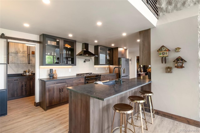 189 Pine Cone Ln, Winter Park, CO 80482 - kitchen featuring wall chimney range hood, appliances with stainless steel finishes, dark countertops, light wood-type flooring, and recessed lighting