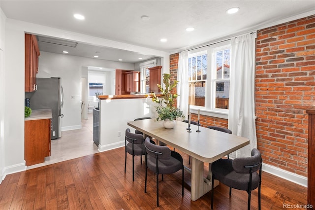 dining room with hardwood / wood-style floors and brick wall