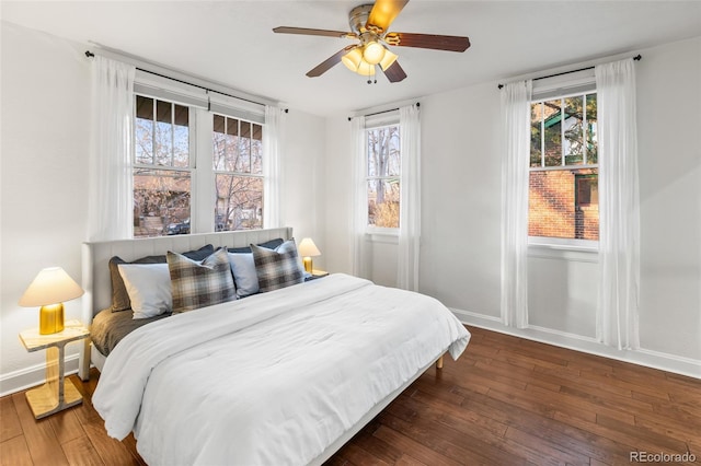 bedroom with ceiling fan, dark hardwood / wood-style floors, and multiple windows