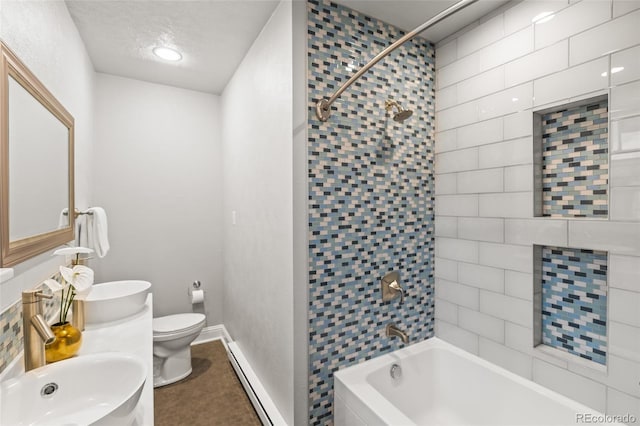 full bathroom featuring toilet, tiled shower / bath, a textured ceiling, baseboard heating, and vanity