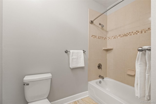 bathroom featuring hardwood / wood-style flooring, toilet, and tiled shower / bath