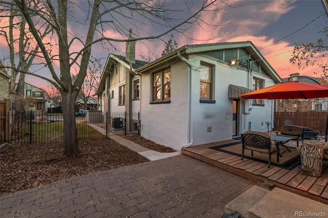 property exterior at dusk featuring cooling unit and a fire pit