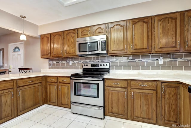 kitchen featuring appliances with stainless steel finishes, brown cabinets, decorative backsplash, and light countertops