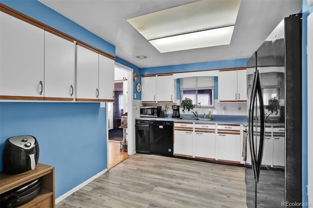 7003 Cleveland Ct, Colorado Springs, CO 80911 - kitchen featuring dishwasher, freestanding refrigerator, stainless steel microwave, white cabinetry, and light wood-style floors