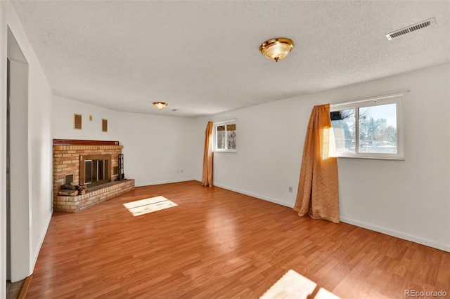 7003 Cleveland Ct, Colorado Springs, CO 80911 - unfurnished living room with a textured ceiling, light wood-type flooring, baseboards, and a brick fireplace