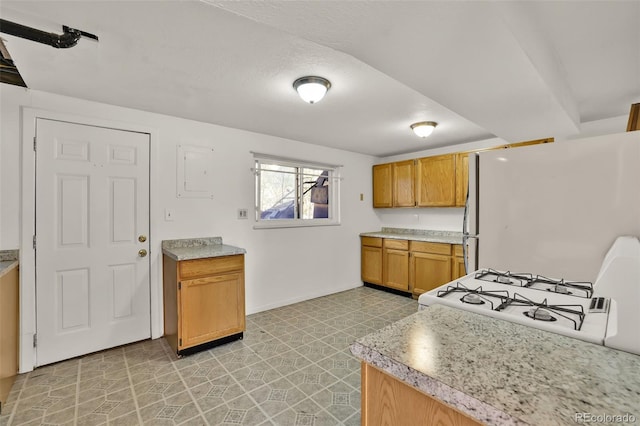 7003 Cleveland Ct, Colorado Springs, CO 80911 - kitchen with white appliances, light countertops, baseboards, brown cabinetry, and light flooring