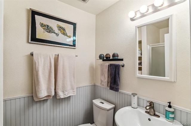 bathroom featuring sink, toilet, and a shower with shower door