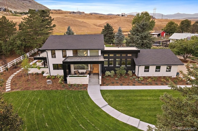 view of front facade with a front lawn, a mountain view, and a patio area