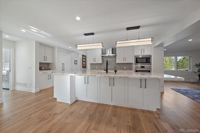 kitchen featuring hanging light fixtures, light hardwood / wood-style flooring, stainless steel appliances, and white cabinets