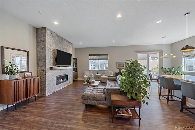 living room featuring a large fireplace, a wealth of natural light, and dark hardwood / wood-style floors