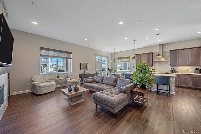 living room with dark wood-type flooring, a textured ceiling, and a notable chandelier