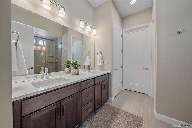 bathroom featuring a shower with door and vanity