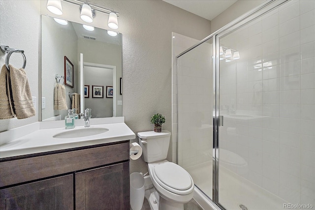 bathroom with toilet, vanity, and a shower with shower door