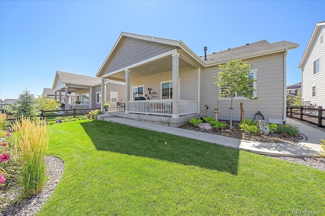 rear view of property with covered porch and a lawn