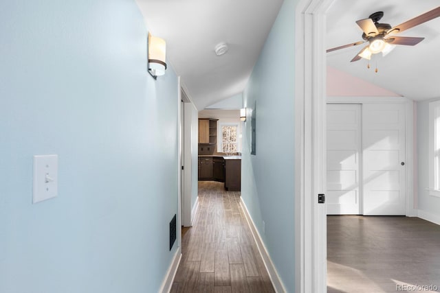 hallway with dark wood-type flooring and vaulted ceiling