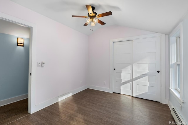 empty room with a baseboard heating unit, dark wood-type flooring, ceiling fan, and vaulted ceiling