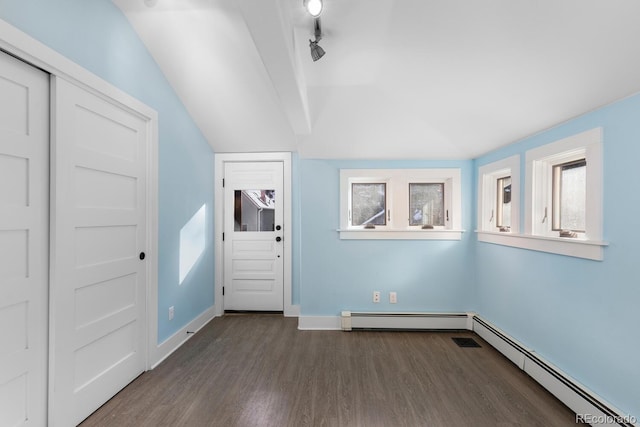 interior space featuring lofted ceiling, rail lighting, a baseboard heating unit, and dark wood-type flooring