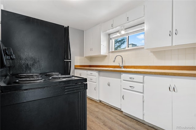 kitchen featuring white cabinets, sink, light wood-type flooring, and backsplash