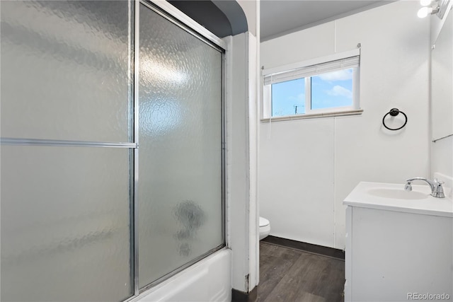 full bathroom with shower / bath combination with glass door, hardwood / wood-style floors, vanity, and toilet