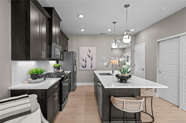 9445 W 58th Cir Unit B, Arvada, CO 80002 - kitchen with stainless steel appliances, backsplash, light wood finished floors, a center island with sink, and light countertops