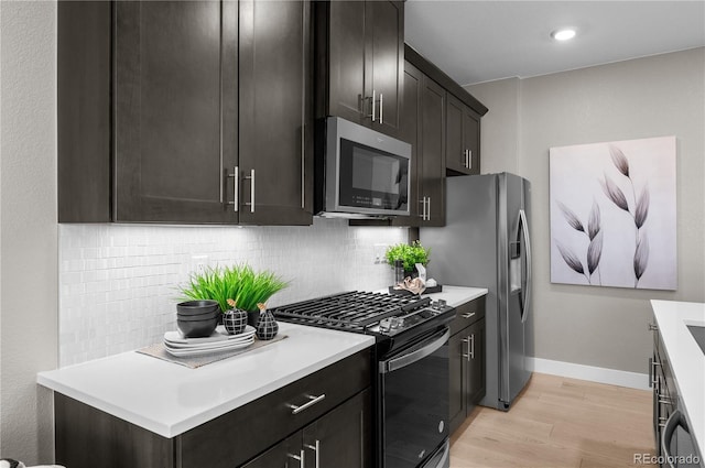9445 W 58th Cir Unit B, Arvada, CO 80002 - kitchen with stainless steel appliances, light wood-type flooring, tasteful backsplash, light countertops, and dark cabinetry