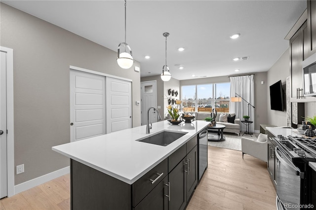 9445 W 58th Cir Unit B, Arvada, CO 80002 - kitchen with stainless steel appliances, light countertops, open floor plan, light wood finished floors, and a kitchen island with sink