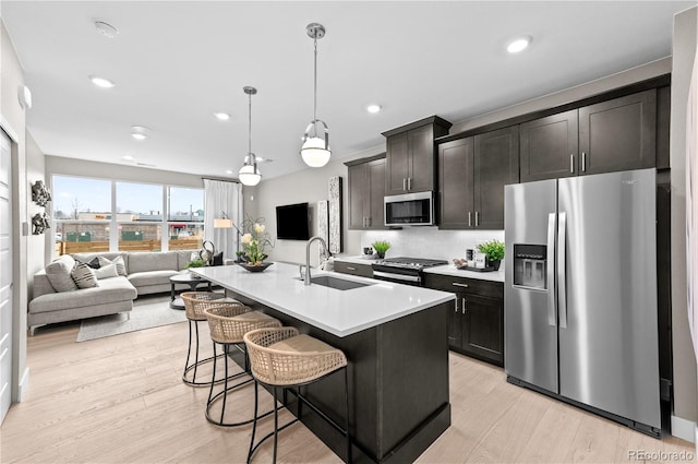 9445 W 58th Cir Unit B, Arvada, CO 80002 - kitchen featuring stainless steel appliances, open floor plan, a kitchen bar, tasteful backsplash, and light wood-style floors
