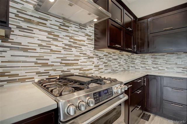 kitchen with tasteful backsplash, wall chimney range hood, dark brown cabinetry, and stainless steel stove