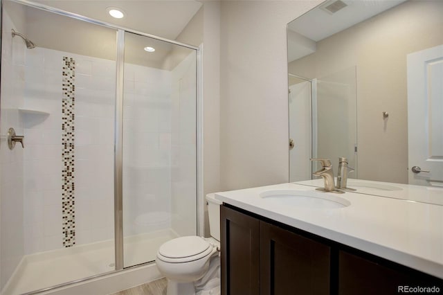 bathroom with toilet, a shower with shower door, hardwood / wood-style floors, and vanity