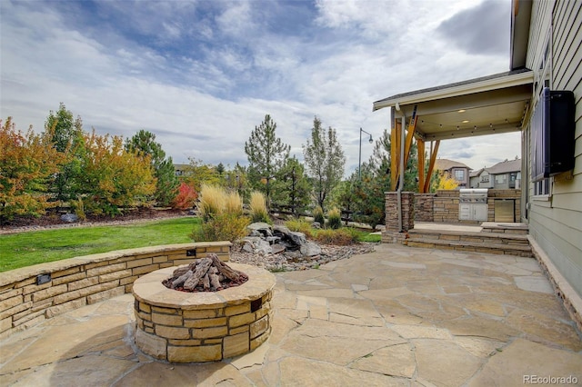 view of patio with an outdoor kitchen and a fire pit