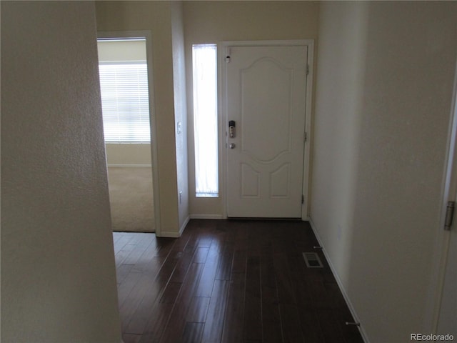 foyer featuring dark wood-type flooring, visible vents, and baseboards