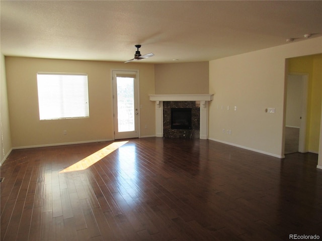 unfurnished living room featuring ceiling fan, baseboards, dark wood-type flooring, and a high end fireplace