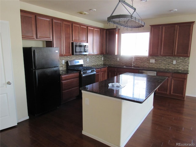 kitchen featuring dark wood-style flooring, tasteful backsplash, appliances with stainless steel finishes, a kitchen island, and a sink