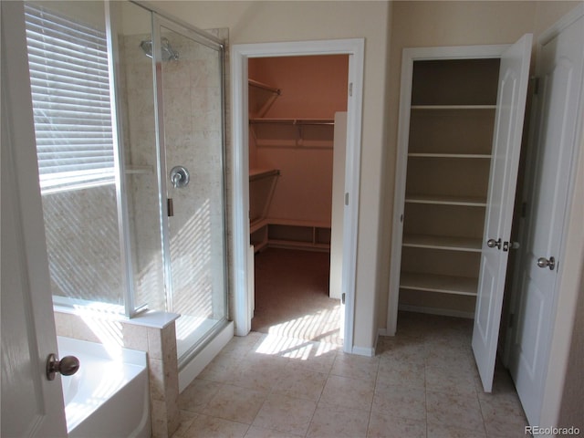 full bath with tile patterned flooring, a walk in closet, a bath, and a shower stall