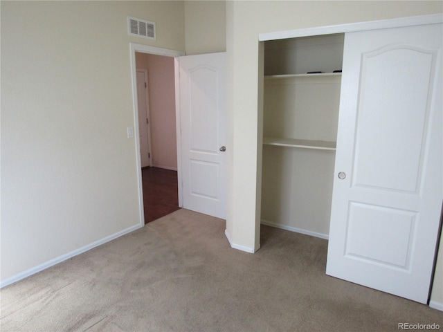 unfurnished bedroom with light carpet, a closet, visible vents, and baseboards