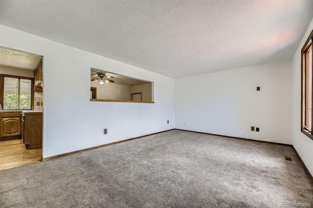 16293 E Brown Pl, Aurora, CO 80013 - spare room with light colored carpet, ceiling fan, a textured ceiling, and baseboards