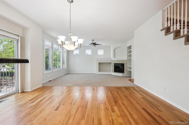 11969 E Lake Cir, Greenwood Village, CO 80111 - unfurnished living room with a chandelier, wood finished floors, a tiled fireplace, and baseboards