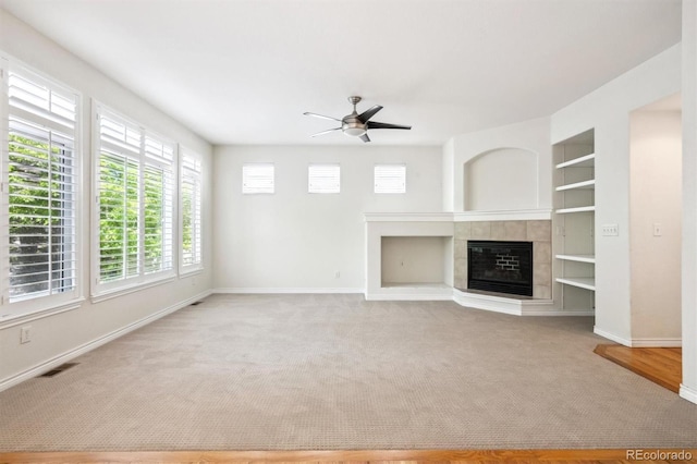 11969 E Lake Cir, Greenwood Village, CO 80111 - unfurnished living room featuring a ceiling fan, baseboards, a tile fireplace, carpet floors, and built in shelves
