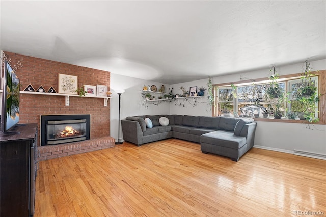 living area with a baseboard heating unit, baseboards, light wood finished floors, and a fireplace
