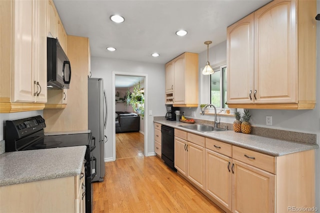kitchen featuring a wealth of natural light, light brown cabinetry, a sink, and black appliances